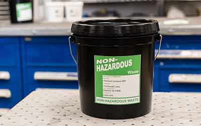 A bright green label on a bucket that says "Non-Hazardous."