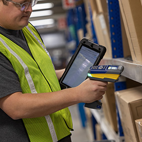 A man using a barcode scanner to check the inventory of items in a warehouse