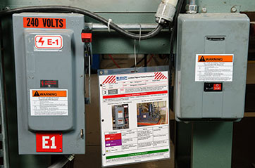 Lockout tagout procedures pamphlet hanging next to control panels in a warehouse.