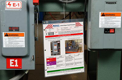 Lockout tagout procedures guide displayed prominently between two electrical panels, facilitating easy access and ensuring the correct application of the lockout system.