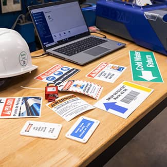 A variety o labels printed with the J7300 printer spread out across a table demonstrating the printer’s ability to print vibrant colors, true blacks, photos, barcodes and other information. 