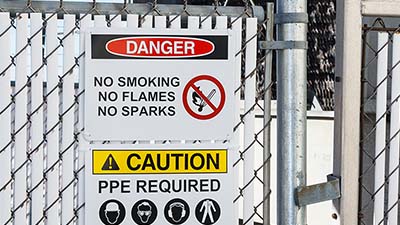 Danger and caution signs on a chain link fence.