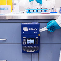 A chemist takes a label from a printer.