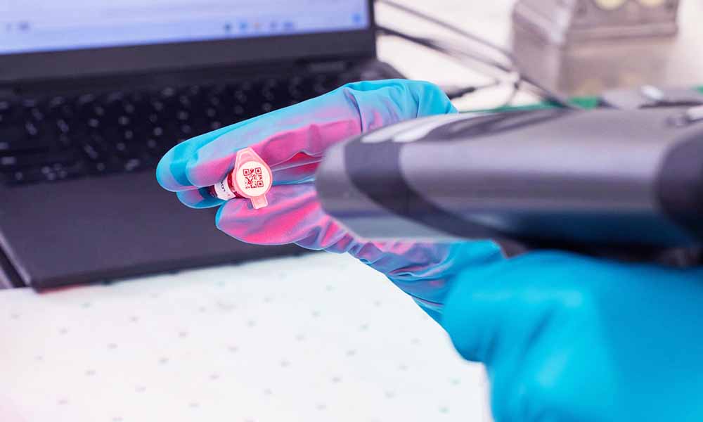 A lab technician scans a small QR code on a vial.