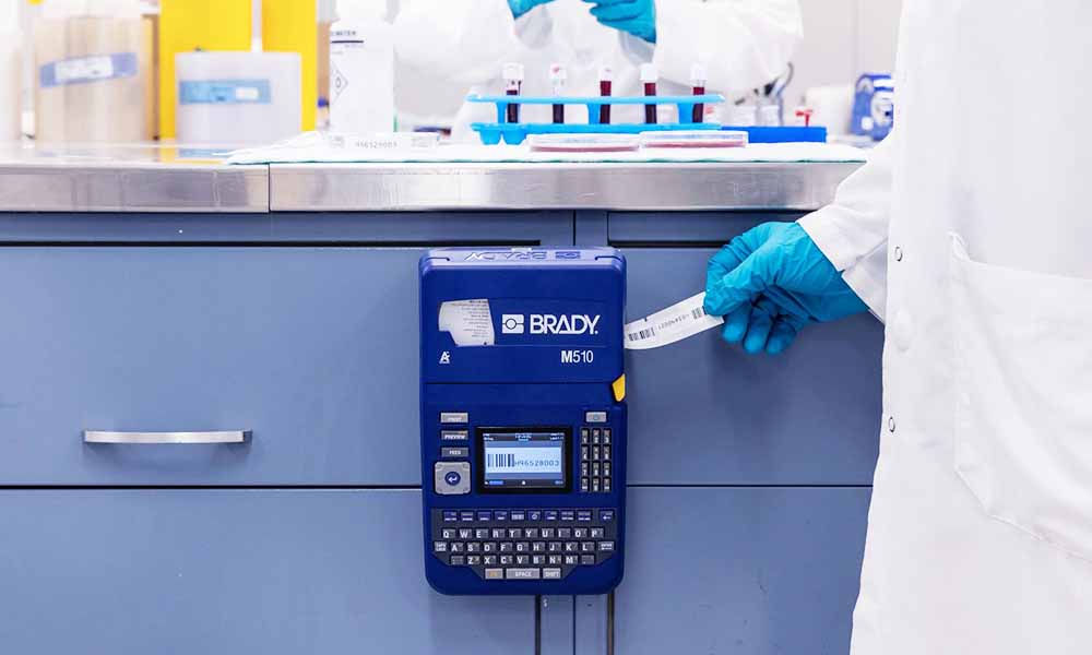 A chemist pulls a label out of an M510 label printer.