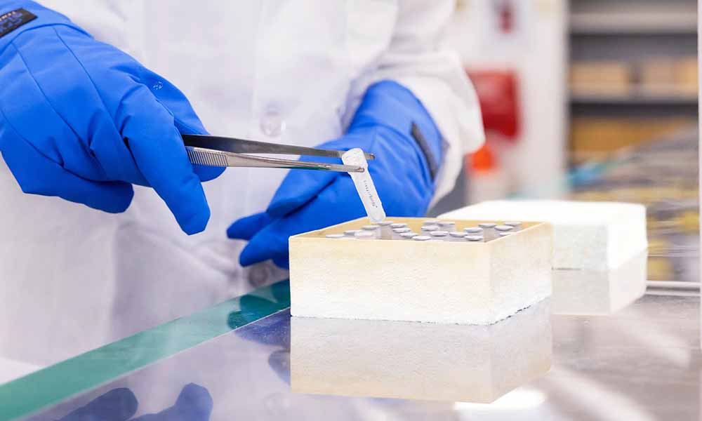 A person uses tongs to pick up a frozen lab vial.
