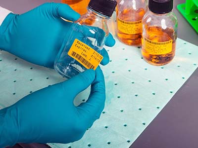 Jars full of liquid are on an absorbent pad.