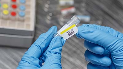 A chemist attaches a barcode label to a vial.