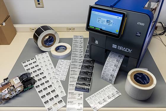 A worker applies an asset tag to a laptop.