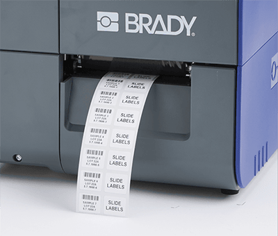 Printed labels exiting a Brady i7500 printer with no wasted label material showing.