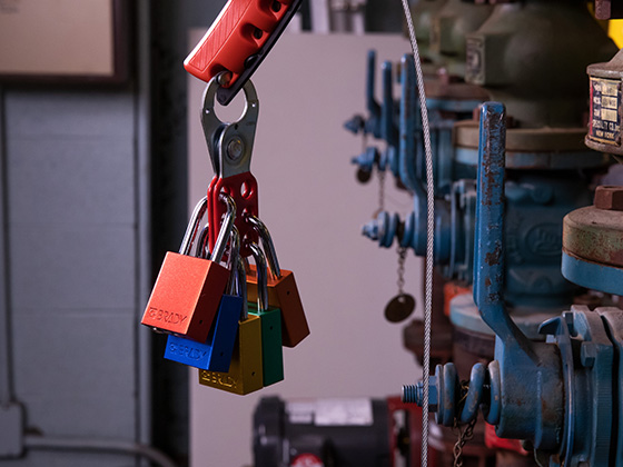 Multiple padlocks hanging from a piece of industrial equipment