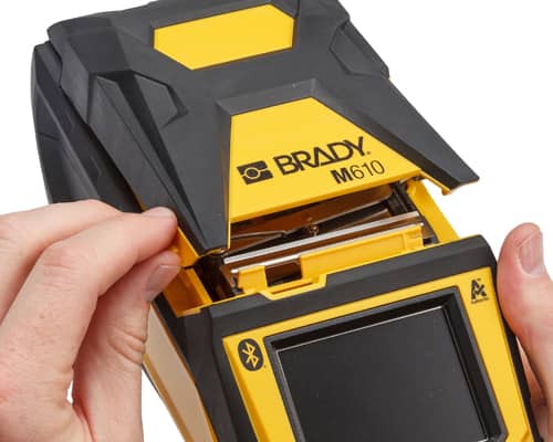 A person opening a Brady M610 printer to change the label material.