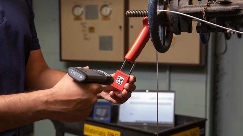 A worker scans a QR code label located on a red lockout padlock.