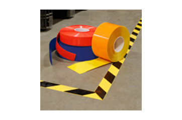 Colorful rolls of floor marking tape on a warehouse floor.