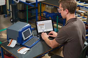A man working at a station with an arc flash label printer.