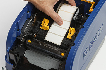 Image of someone loading blank labels into a printer.