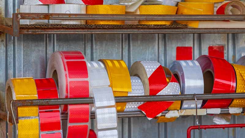 Two racks in an industrial setting holding a variety of DOT reflective tapes.