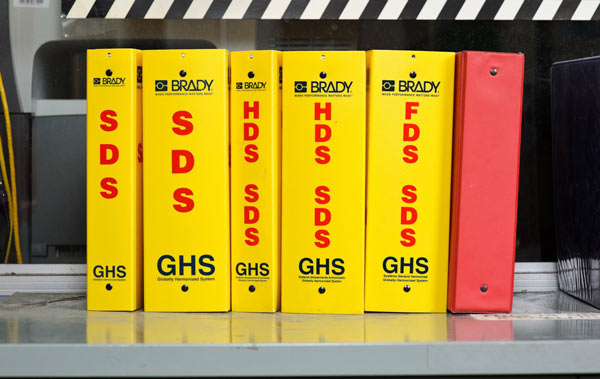 a lineup of bright yellow GHS safety data sheet binders