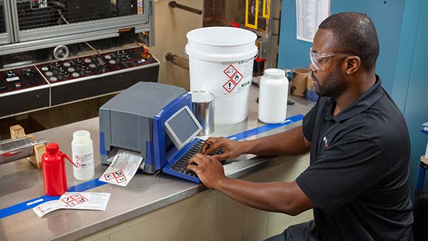 A worker is printing GHS secondary containers labels using a Brady BBP30 GHS label printer.