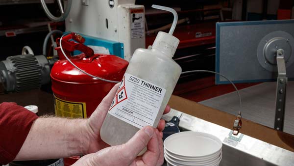A user applies a GHS label to a secondary container in a warehouse setting.