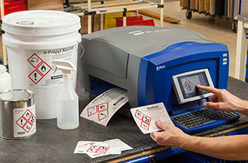 A person printing GHS labels on a Brady desktop printer.