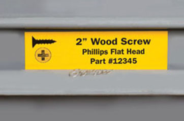 A label that says "2 inch Wood Screw. Phillips Flat Head. Part #12345." it has a scale image of the wood screw from the side and the top. 