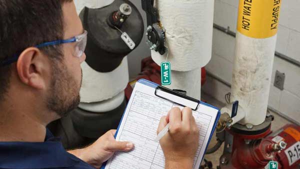 A worker performing a lockout tagout procedure check on a hot water supply pump.