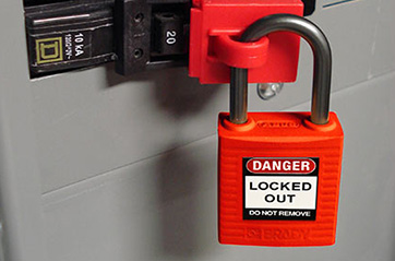 A padlock using a lockout tagout device to secure an electrical breaker.