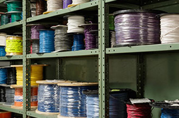 Warehouse shelves with several dozen different colors of wire spindles.