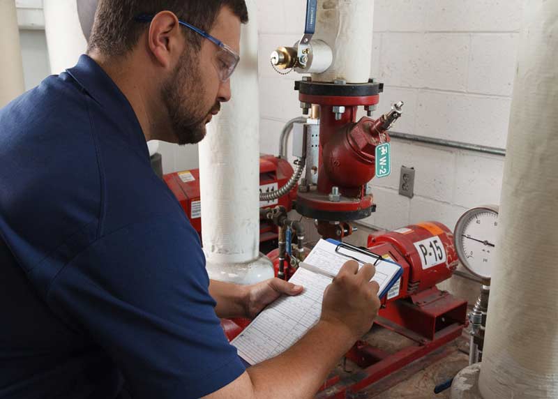 A worker performs a compliance check on a piece of industrial equipment to ensure its in compliance with OSHA regulations.