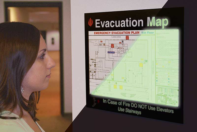 A woman reads an evacuation map that also shows what it would look like glowing in the dark.