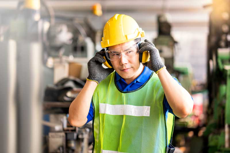 A warehouse employee puts on protective ear muffs.