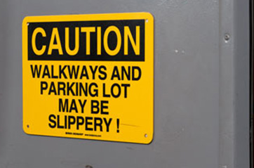 A door sign that says "NOTICE WALKWAYS AND PARKING LOT MAY BE SLIPPERY."