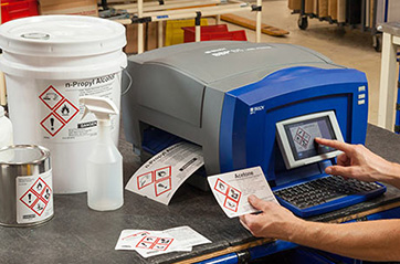 A person printing hazardous material labels on a Brady desktop printer.