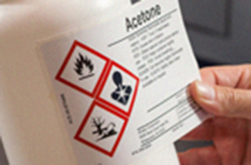 Hazardous material label for acetone being applied to a container.