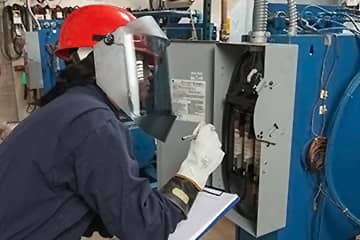 A worker assessing the risk of arc flash for an electrical panel