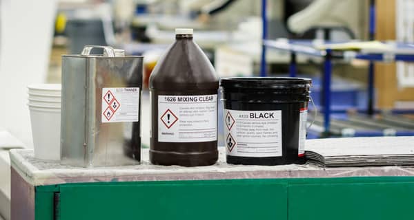 Several chemical containers of different shapes and sizes all showcasing appropriate chemical labels to stay in regulatory compliance.