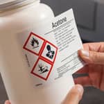 A worker applying a hazardous materials label to a container.
