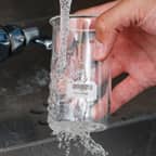 A glass flask with a Brady dissolvable label being cleaned and having the label removed.