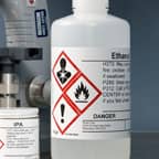 A container of ethanol with a GHS safety label identifying its contents.
