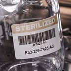 A glass container with a barcode label that identifies it as sterilized.
