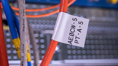 A white cable flag identifying an orange cable within a data center.