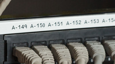 A series of gray cables identified on a patch panel with a white label.