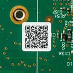 A 2D barcode applied to a green circuit board.