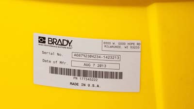 A Brady glossy metallized polyester label applied to the curved surface of a larger cannister.