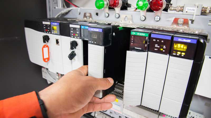 A worker integrating an industrial computer to synchronize with PLC initiatives.