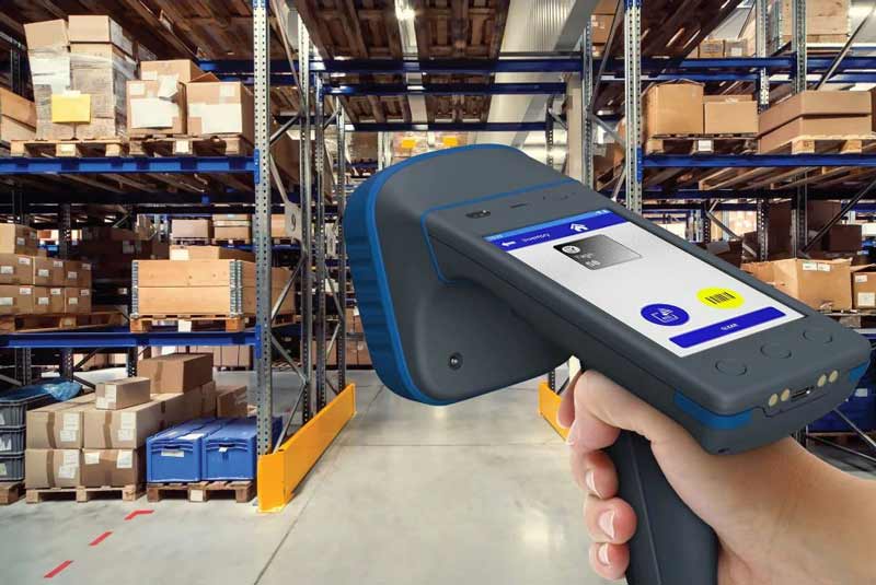 A woman performing asset tracking in a warehouse setting with a handheld RFID reader.